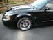 2003 Ford Mustang - A black 2003 Ford Mustang is shown from the front quarter panel, highlighting its wheel and red brake caliper.