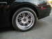 2003 Ford Mustang - Close-up of a black car's rear wheel and fender, showing a chrome rim and red brake caliper.