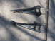 1994 Ford Bronco - Two automotive control arms are shown lying on a concrete surface, casting shadows.