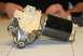 1976 Ford Ranchero - A close-up view of a windshield wiper motor assembly, a black motor and cream-colored housing.