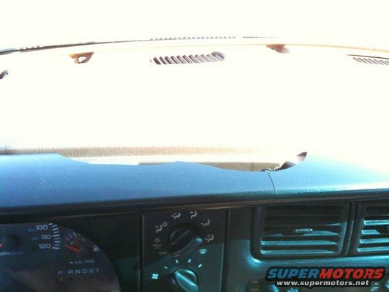 Dashboard interior with speedometer, climate controls, and air vents. The dashboard is cracked