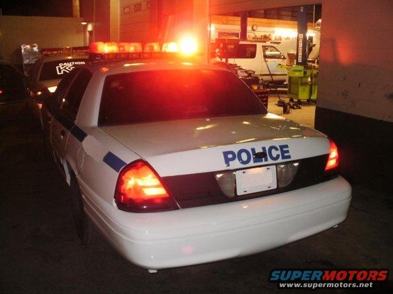 Rear view of a white police car with lights flashing