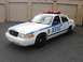 2002 Ford Crown Victoria - White NYPD Ford Crown Victoria police car with light bar parked in front of garage doors.