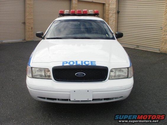 Front view of a white police car with 'POLICE' on the hood and a light bar on top