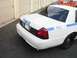 2002 Ford Crown Victoria - Rear view of a white 2002 Ford Crown Victoria police car with blue markings and a light bar.