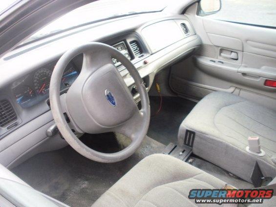 Gray interior of a 2002 Ford Crown Victoria, showing the steering wheel, dashboard, and passenger seat