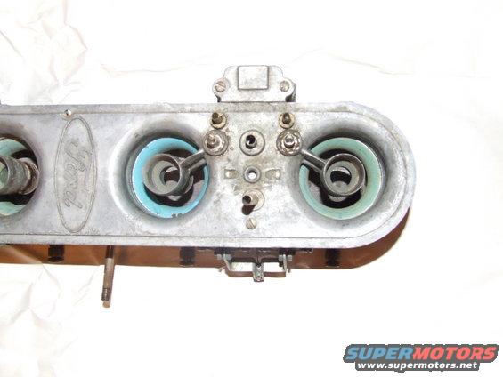 Ford carburetor with two blue-green gaskets and visible Ford oval logo