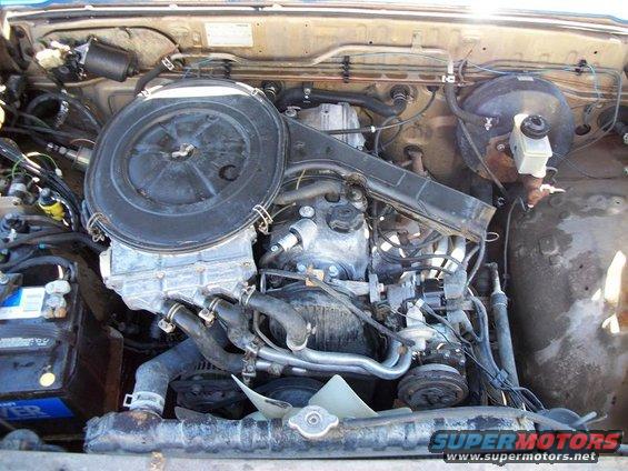 Engine bay with air filter housing, battery, and engine components visible