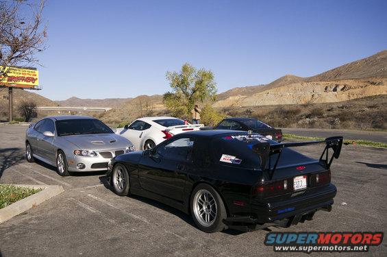 Black Mazda RX-7 with a big wing, silver Pontiac GTO, and white Nissan 370Z parked outside