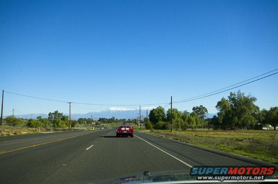 Red sports car driving on a highway with mountains in the background