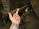 1995 Ford Bronco - A hand gestures obscenely in front of vehicle suspension parts.