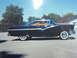 1956 Ford Fairlane - A black 1956 Ford Fairlane sedan is parked in a lot under a clear blue sky.