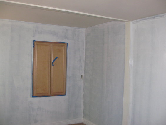 Interior room with light blue walls, a wooden cabinet with two doors, and blue painter's tape