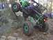 1992 Ford Mustang - A heavily modified off-road buggy navigates a challenging rocky terrain with spectators watching.