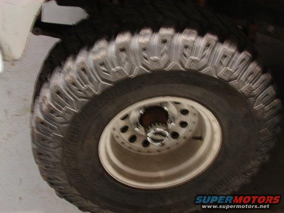 Close-up of a large off-road tire and white rim with Supermotors logo