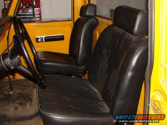 Yellow truck interior showing black vinyl seats with ribbed pattern and a black steering wheel