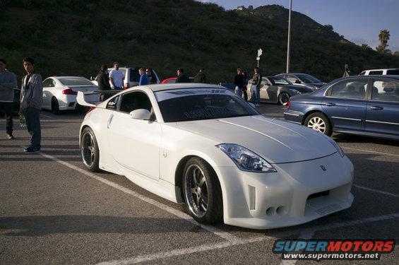 White Nissan 350Z with aftermarket body kit and spoiler, parked in a lot