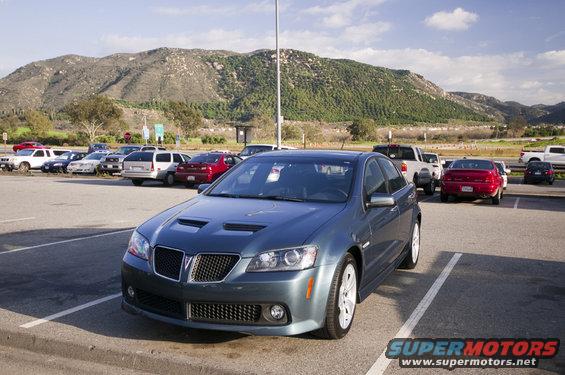 Blue sedan with hood scoops parked in a lot