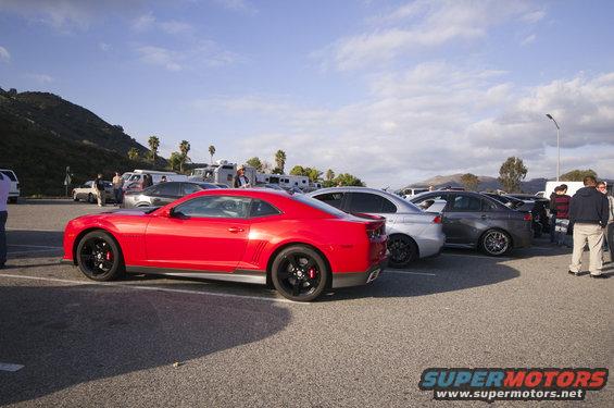 Red coupe with black wheels and red brake calipers, parked in a lot