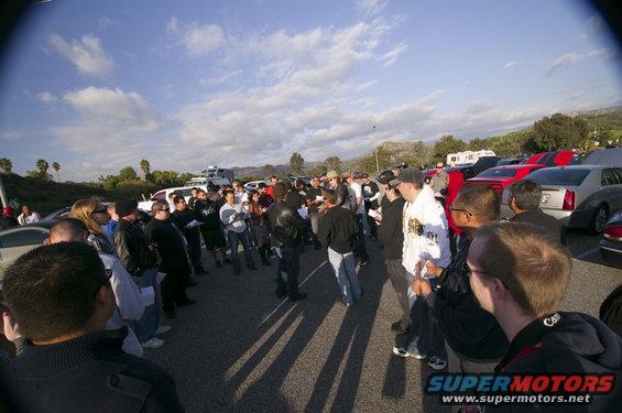 Silver 2006 Cadillac STS parked in a lot with other cars and a crowd of people