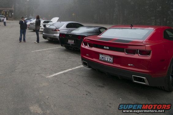 Red Chevrolet Camaro SS with black racing stripes and license plate 6MDL135 parked in a lot