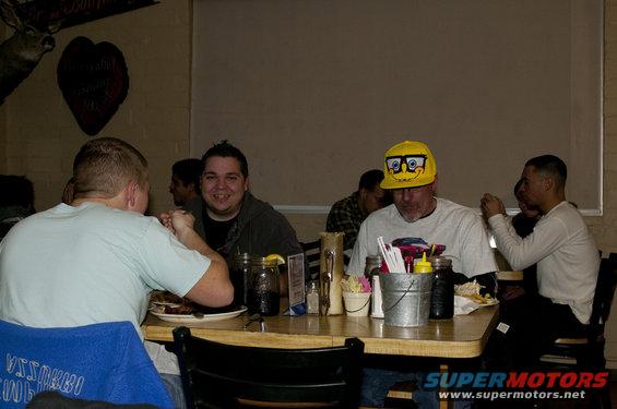 People sit at a table in a restaurant, with a deer head mounted on the wall