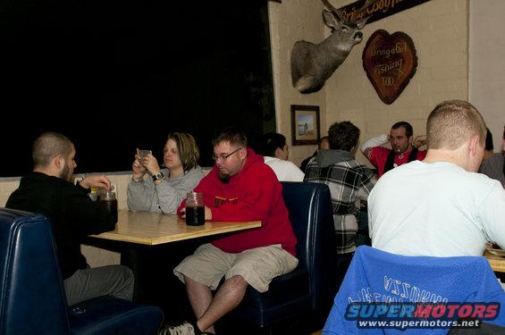 People seated at tables in a restaurant with a mounted deer head on the wall