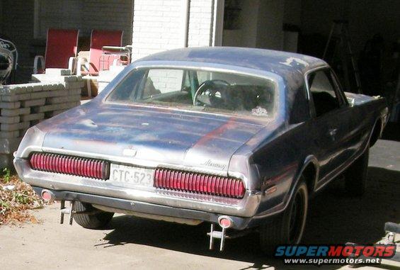 Blue 1968 Mercury Cougar with a dented rear bumper and faded paint, seen from a rear-quarter angle