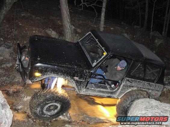 Black 1977 Ford Bronco off-roading over rocks