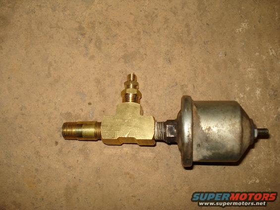 Brass T-fitting connected to a silver pressure sensor, lying on a concrete surface