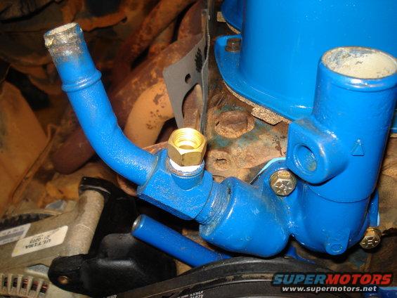 Close-up of blue-painted engine coolant pipes and fittings, with some rusty engine components visible