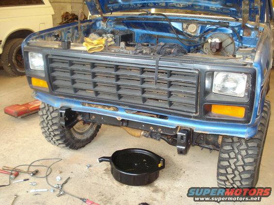 Blue Ford F-series truck with hood open, front grille, and oil drain pan on the floor