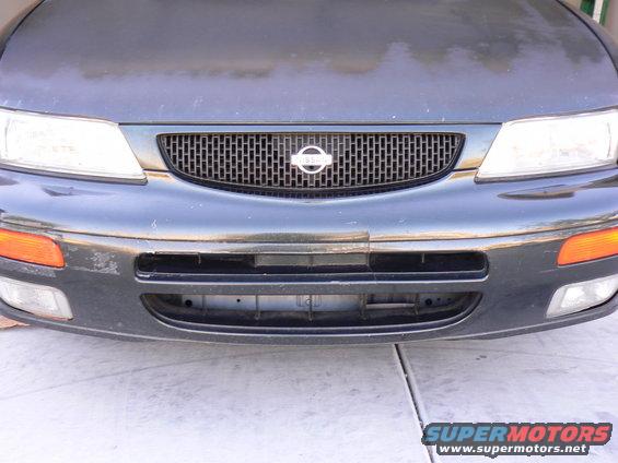 Front of a dark-colored Nissan sedan showing the grille with a Nissan badge, headlights, and bumper