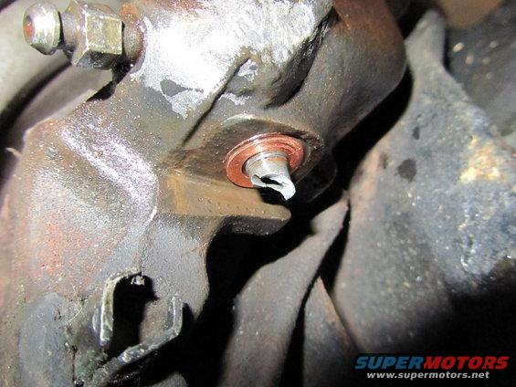 Damaged drain plug with copper washer on a greasy metal housing