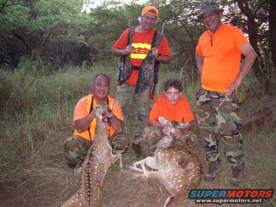 Hunters with two deer, one held up by a hunter