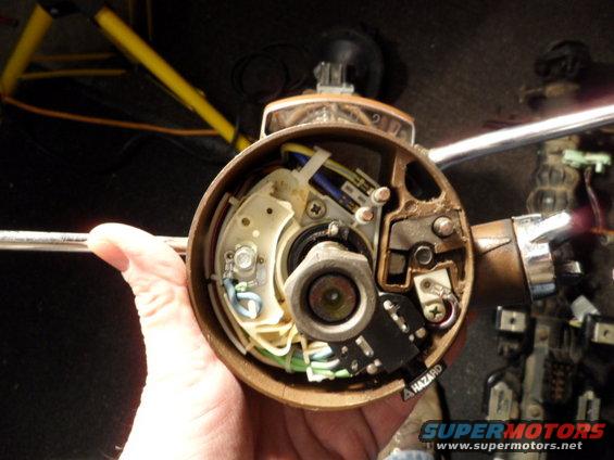 Close-up of a steering column ignition switch assembly with wiring and hazard switch