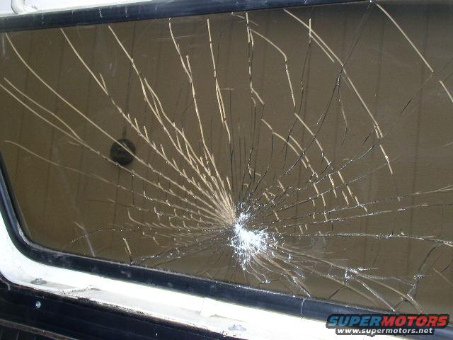 Close-up of a shattered vehicle window with a spiderweb crack pattern