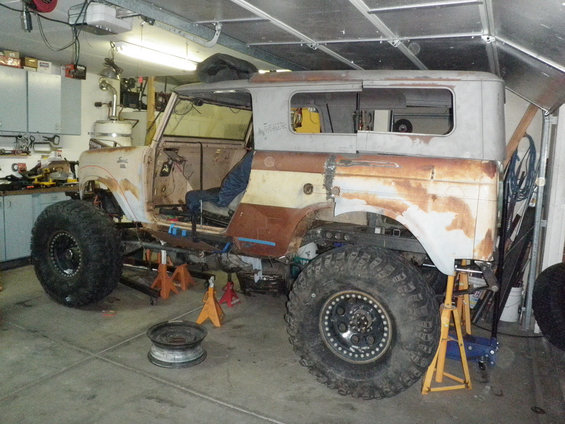 1961 International Scout 800 body on jack stands in a garage, missing doors and roof panels