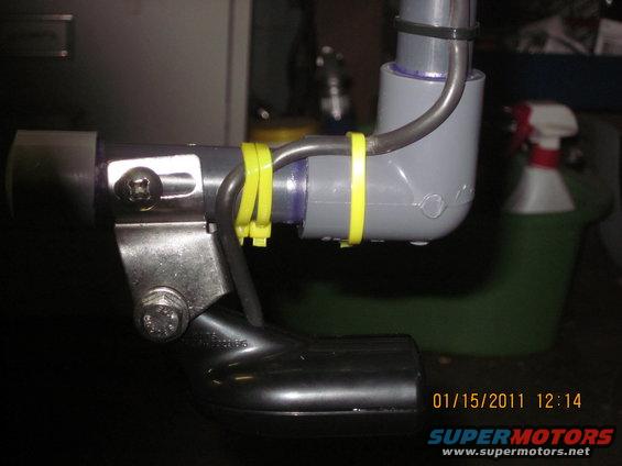 Close-up of plumbing with yellow zip ties and a black elbow piece