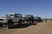 1991 Ford Bronco - A convoy of Ford Broncos is lined up on a dusty track under a bright, cloudless sky.
