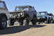 1991 Ford Bronco - A line of Ford Broncos are parked on a dusty trail under a clear blue sky.