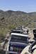 1991 Ford Bronco - A line of off-road vehicles navigates a desert trail, with a classic Ford Bronco leading the pack.