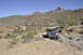 1991 Ford Bronco - Several SUVs navigate a challenging off-road trail through a desert landscape with mountains in the background.