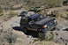 1991 Ford Bronco - Multiple Ford Broncos navigate a challenging off-road trail in a desert landscape.