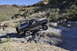 1991 Ford Bronco - A dark gray 1991 Ford Bronco navigates a challenging rocky terrain under a clear blue sky.