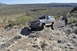 1991 Ford Bronco - A lifted Ford Bronco navigates a challenging rocky terrain in a desert landscape.