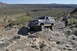 1991 Ford Bronco - A gray Ford Bronco navigates a rocky off-road trail with other vehicles following behind.