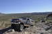 1991 Ford Bronco - A dark gray 1991 Ford Bronco navigates a , rocky desert path under a clear blue sky, with another off-road vehicle following.