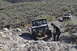 1991 Ford Bronco - Two off-road vehicles tackle a steep, rocky incline in a desert landscape.