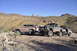 1991 Ford Bronco - Modified Ford Broncos are parked in a desert area with mountains in the background.